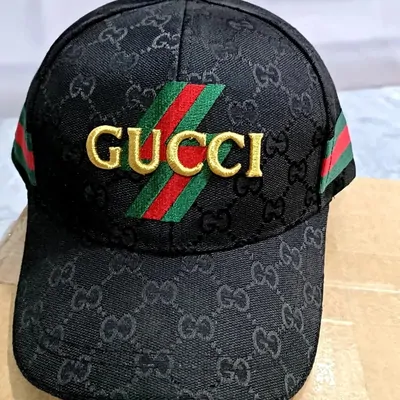 A black monogram canvas baseball cap, gold lettering across the front and a green and red stripe running over the crown.