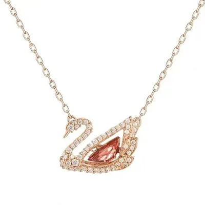 A fine rose gold chain with a swan pendant, its body a single pink stone and its wing set with small clear stones, on white.