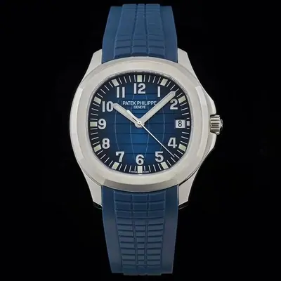 A steel watch with a blue embossed dial, applied numerals and a date window, on a blue rubber strap against black.